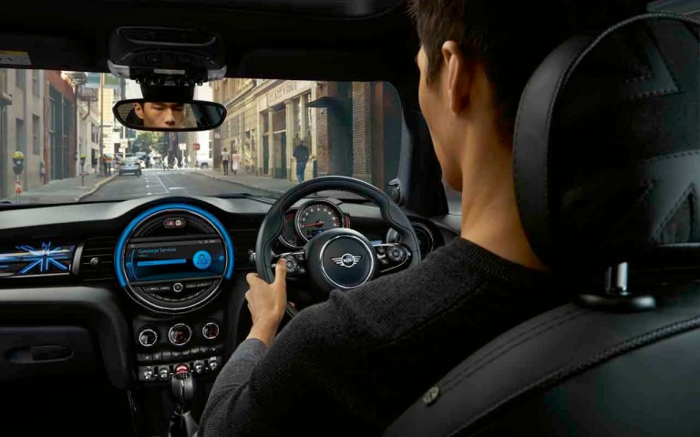 Man driving MINI view of steering wheel and dash