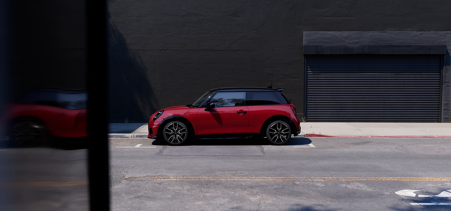 Side view of the MINI Cooper in Chili Red and Black Roof parking.