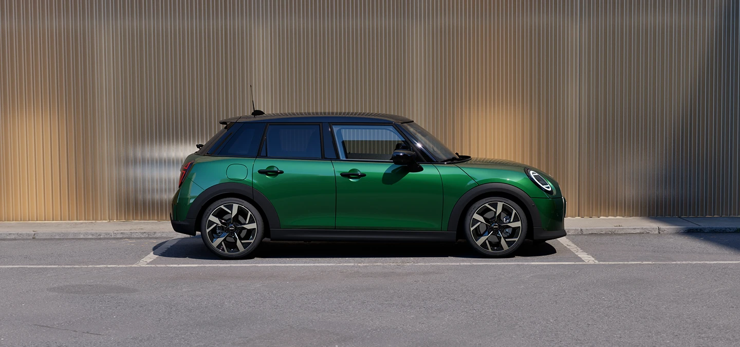 Side view of the MINI Cooper 5-Door in British Racing Green and Roof in Black parking.