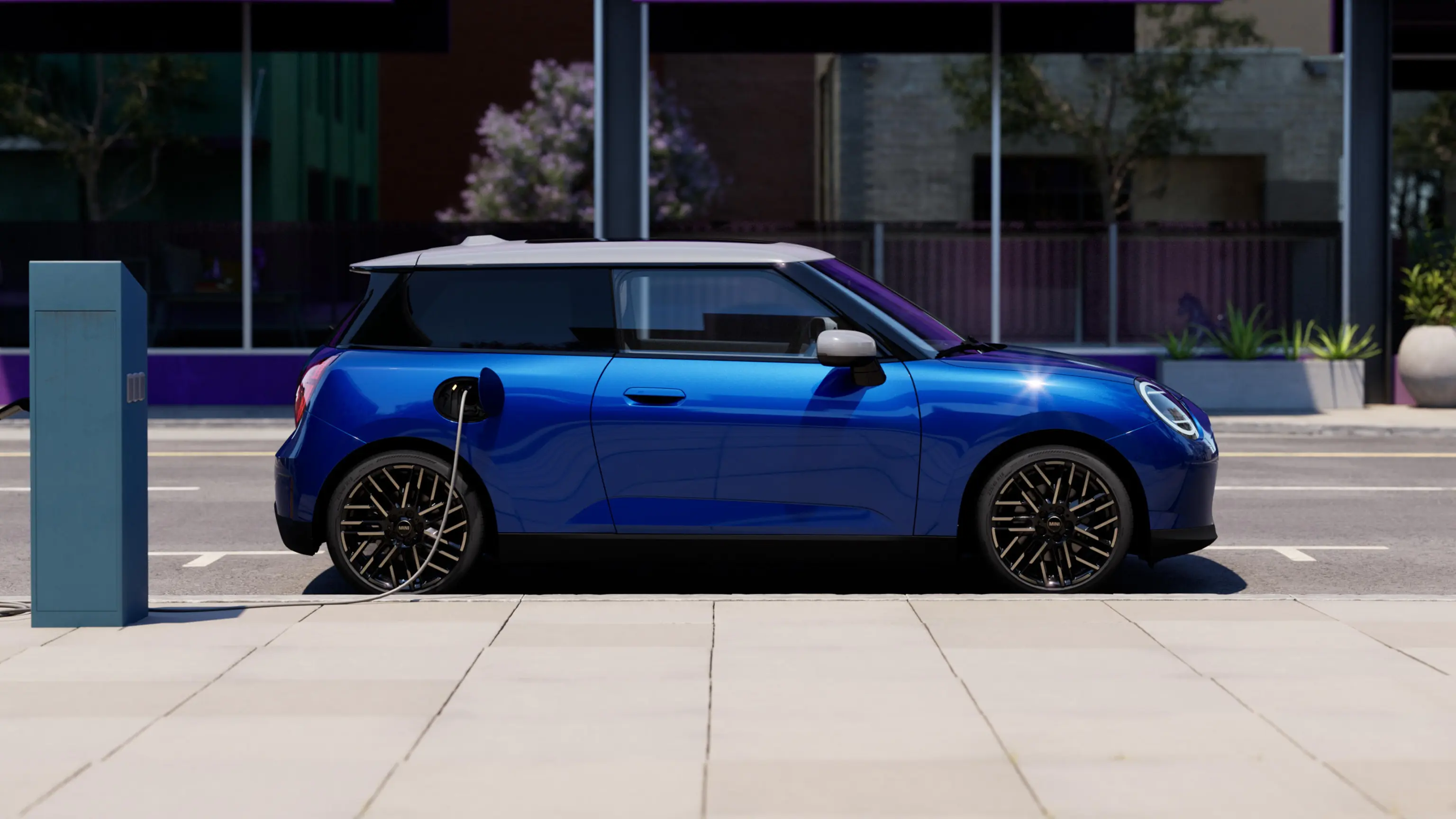 Side View of Blazing Blue all-electric MINI Cooper parked on pavement beside a charging station