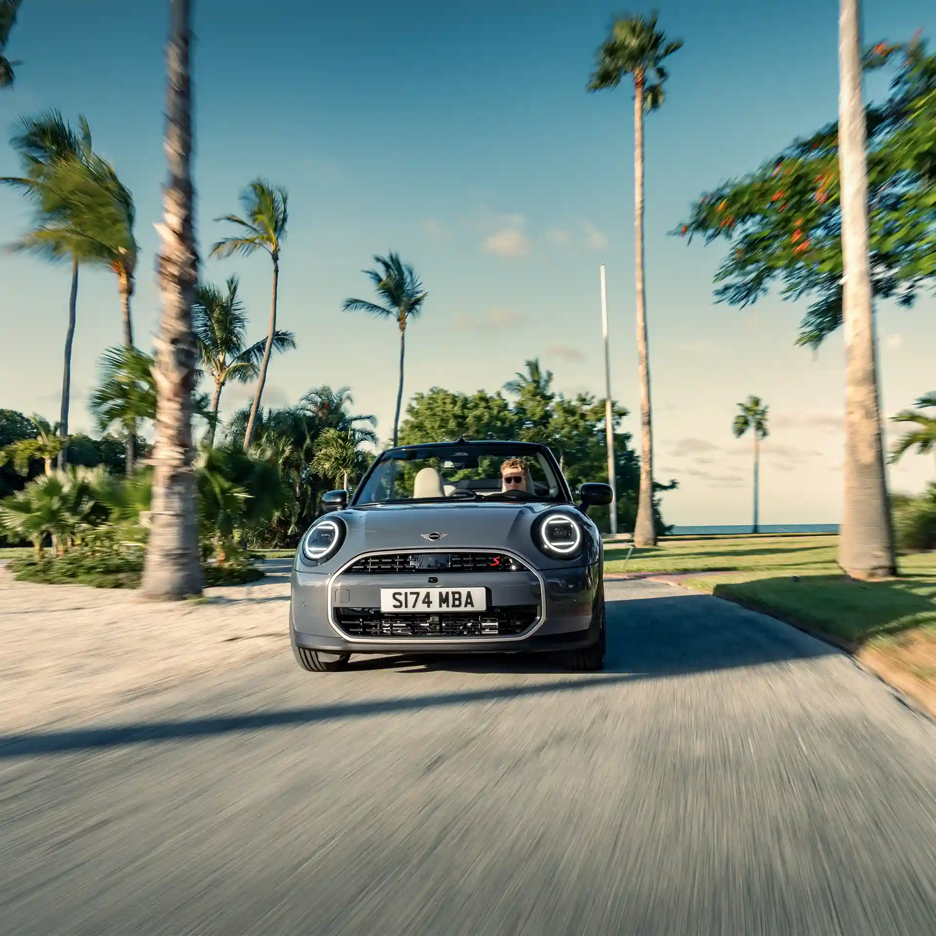 Frontal view of a driving MINI Cooper Convertible in Copper Grey on a street