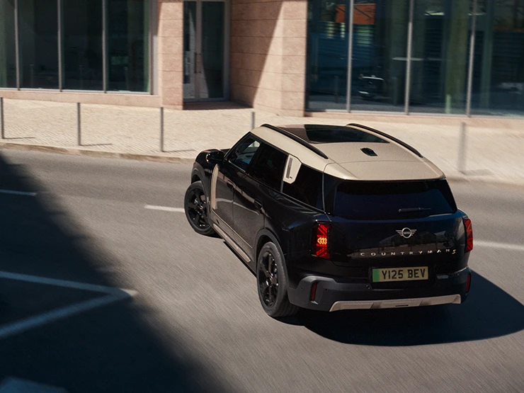 Rear top view of the all-electric MINI Countryman in Midnight Black with Vibrant Silver Roof parking,