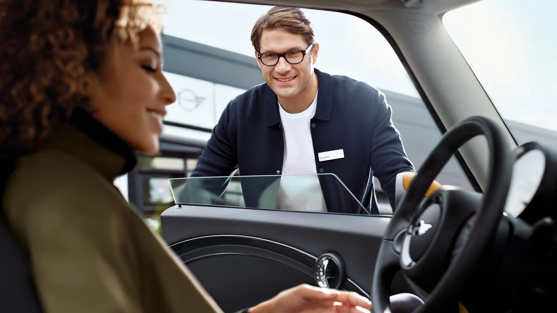 MINI employee greets service customer.