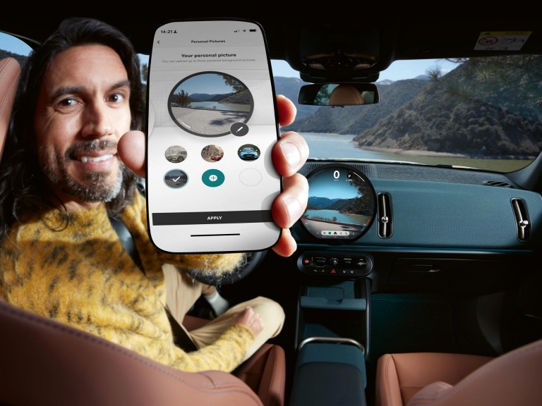 Man in car displaying The MINI App on his mobile