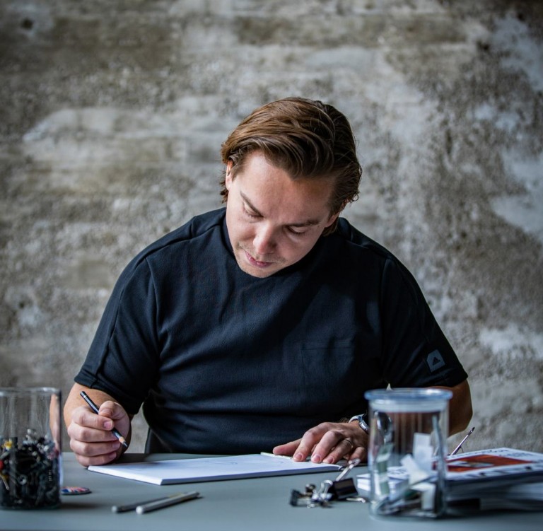 MINI Automotive Designer Josef Kuhlmann sitting at a desk drawing a MINI.