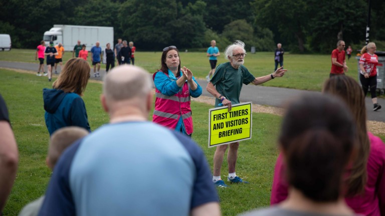 Old man with yellow sign "First timers and visitor briefing"