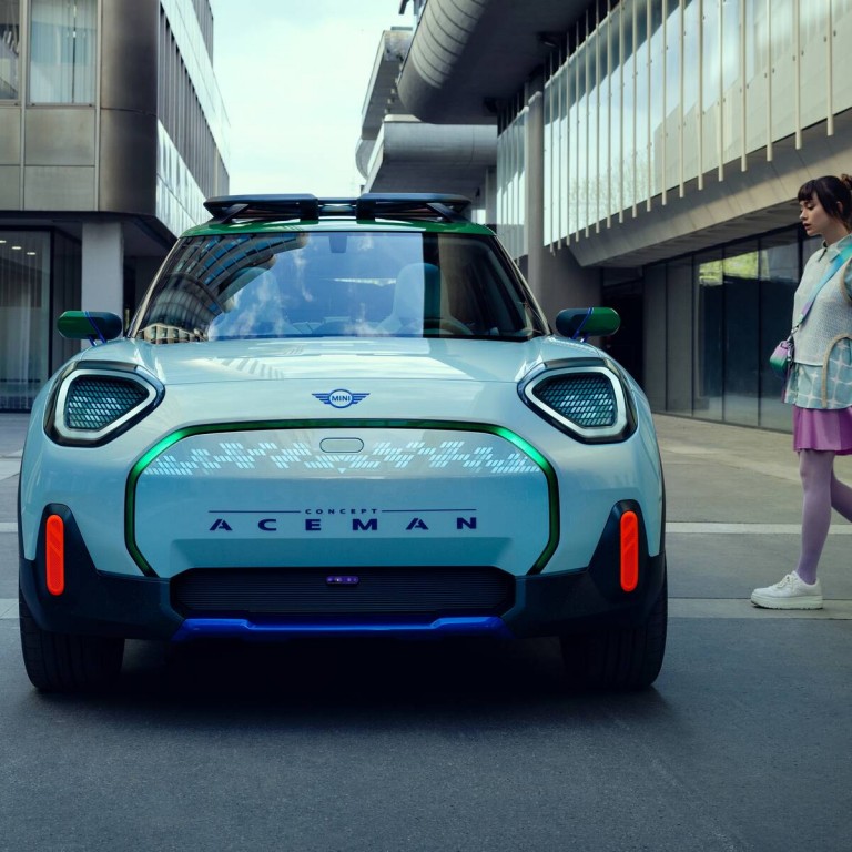 Lawena stands in front of her designed and colourful Mini classic. The side of the car reads “BIG LOVE”. 