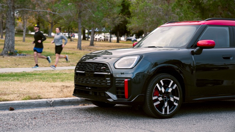 Two joggers jogging past a parked MINI Countryman