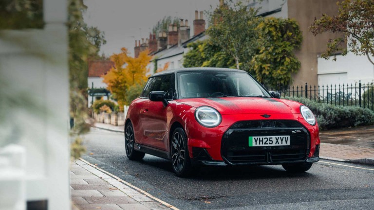 A yellow MINI Cooper car parked on a cobblestone street beside brick buildings.
