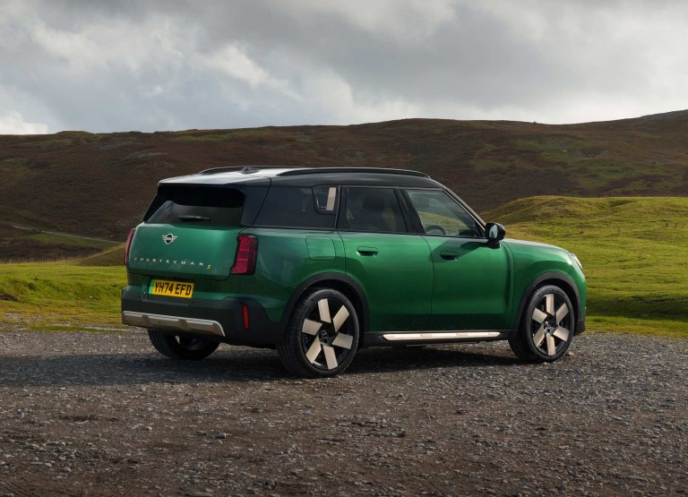 Front view of the all-electric MINI Countryman in Midnight Black and Vibrant Silver Roof on a street.