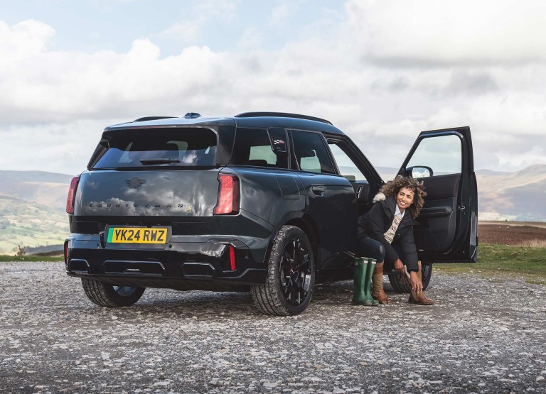 Rear view of the all-electric MINI Countryman in Smokey Green and Vibrant Silver roof parking. 