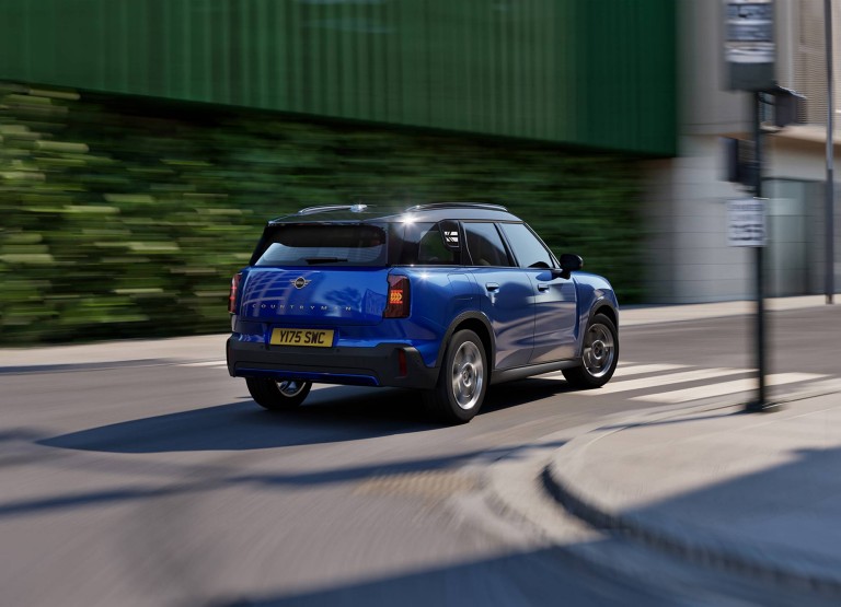 Side rear view of the MINI Countryman in Nanuq White with Black Roof standing on a street.