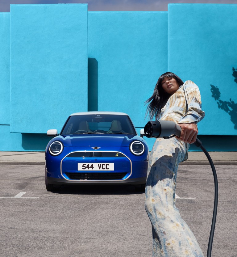 Man charging parked white Nanuq white MINI Electric 